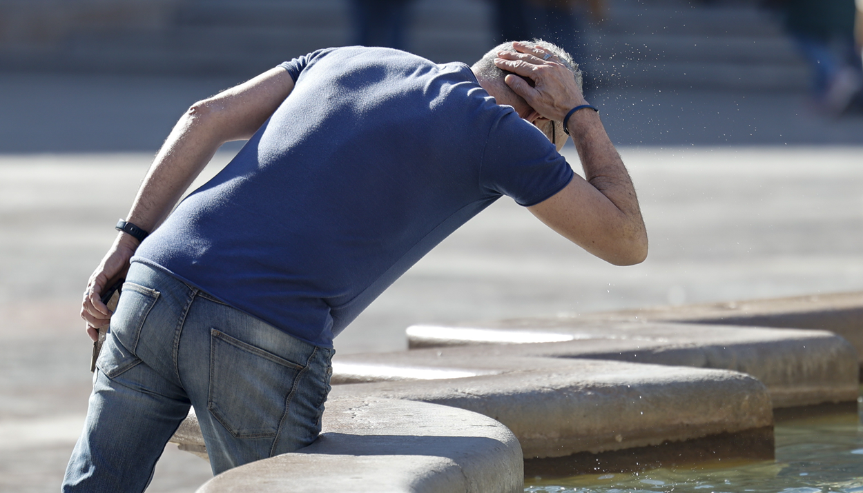 Άνθρωπος προσπαθεί να δροσιστεί από συντριβάνι στην Ισπανία © EPA/BIEL ALINO